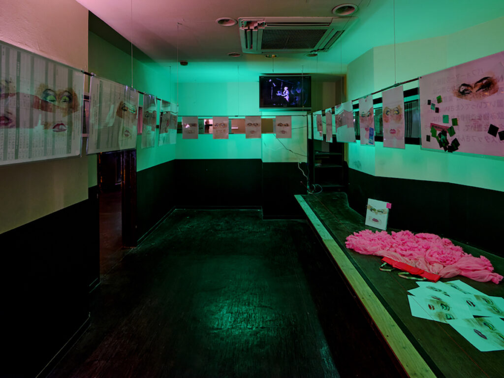 ＜2階＞ ビデオ, 1時間4分18秒, 日本のドラァグクィーンのパイオニアのひとりであるMONDOが続けてきた「顔拓」。個人的な営みであり、作品として発表するのは本展が初めてとなる。布を支持体とする歌舞伎の隈取りと異なり、化粧を剥がし移した透明のテープを楽屋などにあった資料など紙の裏面に貼り付けてある。早くからメジャーシーンでドラァグクィーンを起用してきたMISIAとの繋がりなども読み取れる。（撮影：森田兼次）