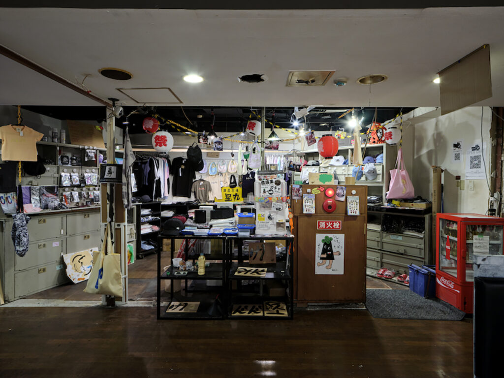 ＜1階＞「金三昧」Chim↑Pomが2014から続けるショッププロジェクト「金三昧」のポップアップ。高円寺キタコレビル、秋葉原3331、六本木の森美術館、渋谷パルコなどを巡回し、今回はミュージアムショップとして王城ビルに開店。通常高額で取引きされる作品と市場に値段が決定される商品の境界線を探り、経済的価値と無価値の間を行き来する。（撮影：森田兼次）