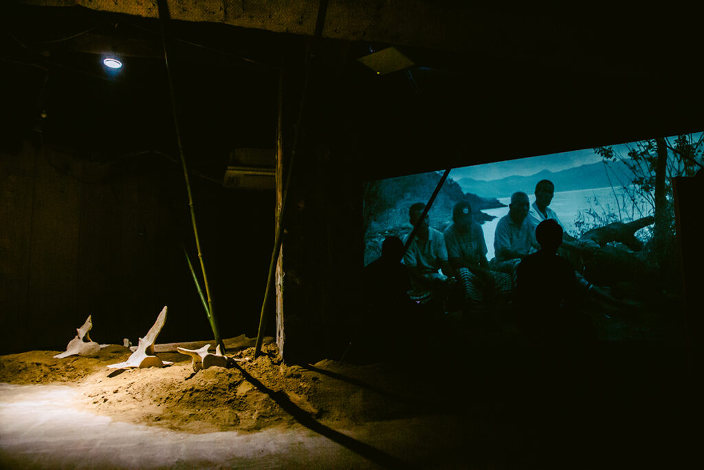 プログラム：王城ビル(A)-①チェン・ティエンジュオ　ソロ・エキシビション｜Asian Dope Boysとして知られるチェン・ティエンジュオが、王城ビルの2フロアを使い、壮大なインスタレーションを展開する。彼とダンサーのシコ・スティヤントは、インドネシア・ラマレラ村の伝統捕鯨から着想を得て、儀式を公演とした。本展では、この要素を展示として構成し、雄大な風景を作り出す。鯨を追い、信仰と文化が交わる村の伝統が、今や近代化の波に脅かされ、共生と存続の危機に晒される姿が映し出される。（撮影：上原俊）